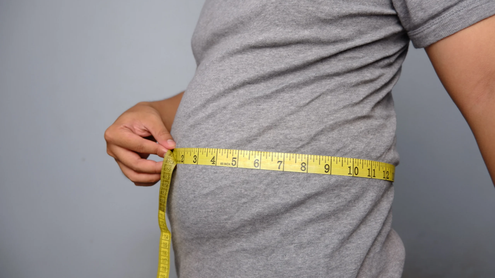 adult-measuring-waist-with-yellow-tape-measure-2026-03-18-12-19-15-utc