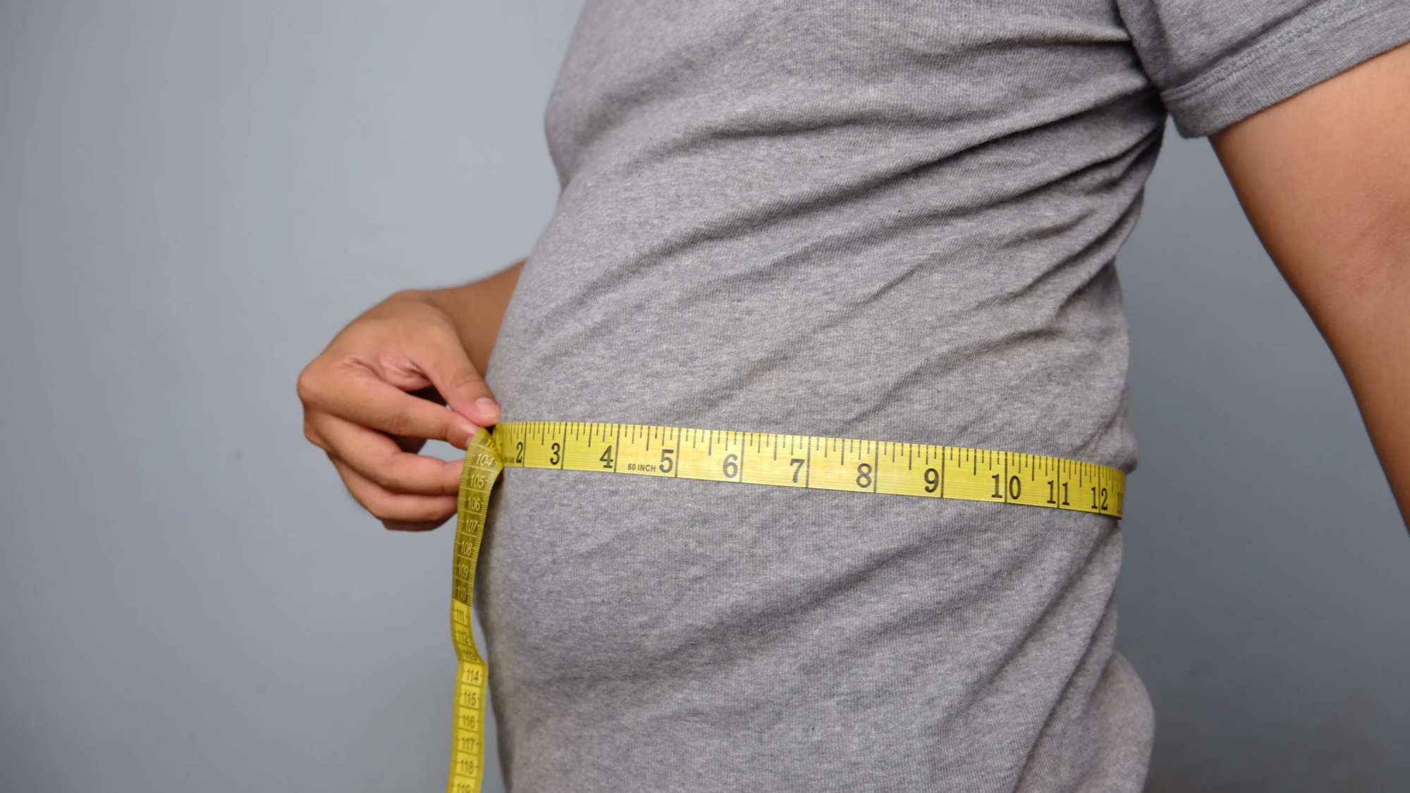 adult-measuring-waist-with-yellow-tape-measure-2026-03-18-12-19-15-utc